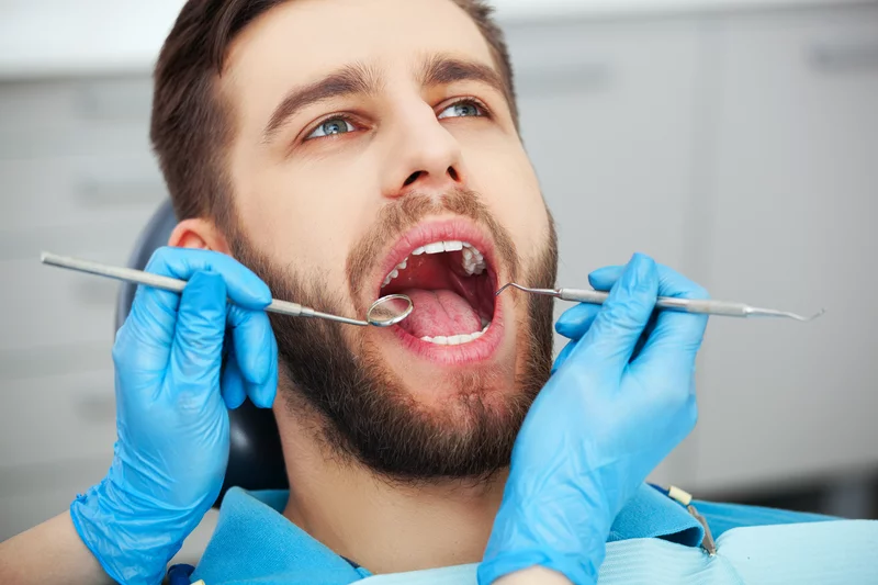 mężczyzna z otwartą szczęką u dentysty